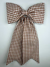 Brown and white checkered bow on a light gray background