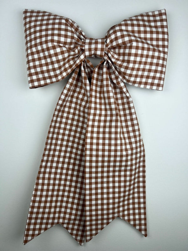 Brown and white checkered bow on a light gray background