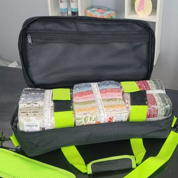 Black travel bag with colorful fabric rolls inside, on a gray surface.