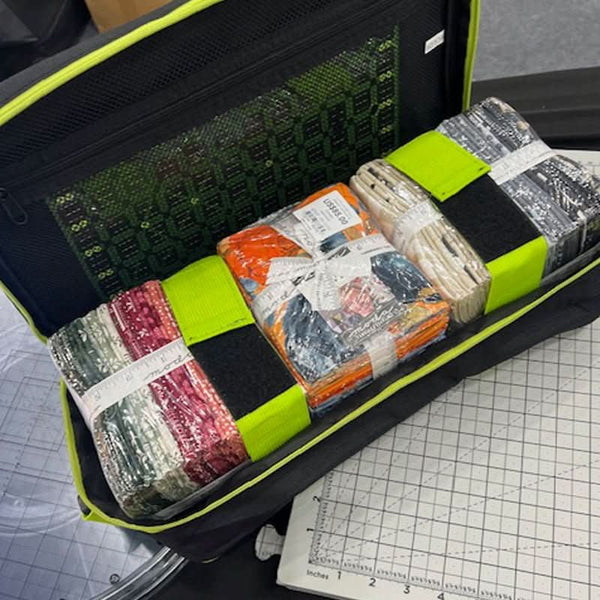 Packages wrapped in colorful materials inside an open suitcase on a grid surface