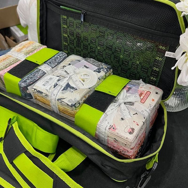 Green and black suitcase with packed items including books and a bag.