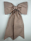 Brown and white checkered bow on a light gray background